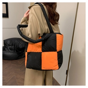 Detailed view of black and orange checkerboard quilted puffer tote bag with padded handles