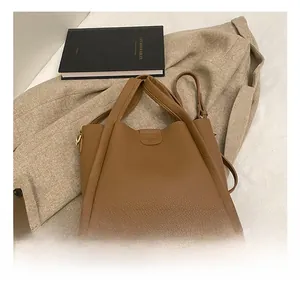 Detail of brown litchi pattern leather bucket bag with wide handles and gold hardware