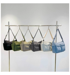 Détail de grands sacs à bandoulière en nylon en six coloris suspendus sur un présentoir