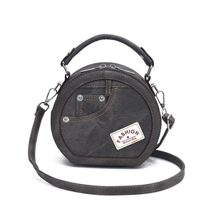 Deep grey denim circle crossbody bag with top handle and vintage pocket design