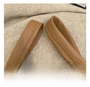 Detail of reinforced double stitching on caramel leather bag handle with premium texture