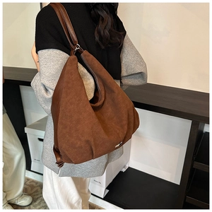 Detail of a brown matte PU leather shoulder bag featuring a side metal logo and long strap