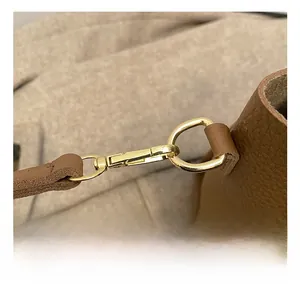 Close-up of golden metal swivel hook and D-ring on brown lychee texture leather bag