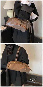 Detailed side view of a brown faux leather baguette bag with a mini pouch attachment
