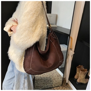 Detail of a dark brown matte crescent hobo bag featuring contrasting white hand-stitching
