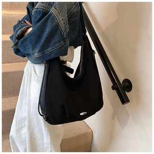 Detail of a large black crescent tote bag with metal accent and premium stitching