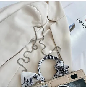 Detail of beige camera bag with silver snake chain and silk scarf wrapped handle