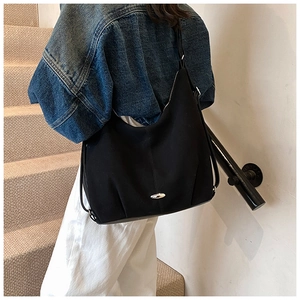Detail of a black canvas hobo bag with silver metal buckle on a model going up stairs