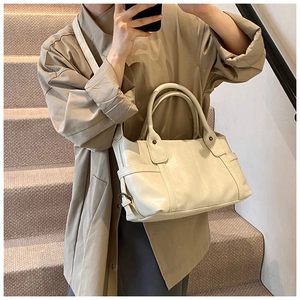 Detail view of large cream tote bag with adjustable side straps and textured finish