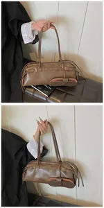 Detail of coffee brown baguette shoulder bag with matte leather finish and small pouch