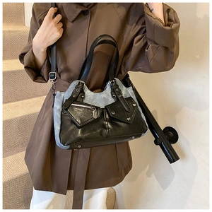 Detail of vintage patchwork shoulder bag with denim texture and silver buckle accents