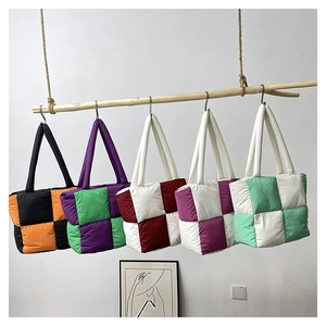 Detail of colorful puffer tote bags in quilted checkerboard patterns on a wooden rack