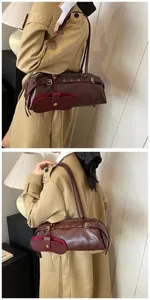 Detail of burgundy baguette shoulder bag with metal buckle and hanging accessory pouch