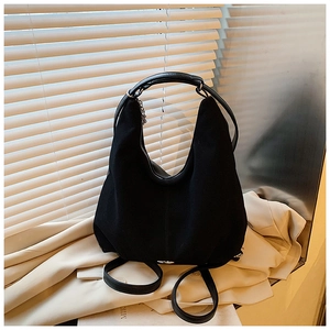 Detail of matte black suede tote bag showing leather straps and metal zipper closure