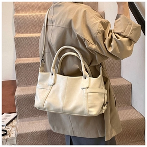 Detail of cream white PU leather tote bag featuring side pockets and dual handle straps
