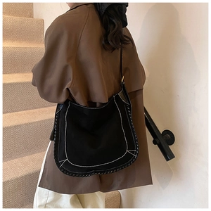 Detail of black suede hobo bag with contrast white stitching on a female model
