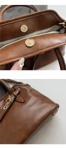 Detail of gold magnetic buckle and brown oil wax leather texture on large tote bag