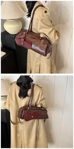 Detailed view of a vintage brown leather baguette bag with metal buckle and small purse pouch