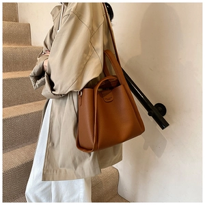 Close-up of brown litchi pattern leather bucket bag with top handle and shoulder strap