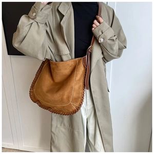 Detail of brown faux suede saddle bag with decorative contrast stitching and leather strap