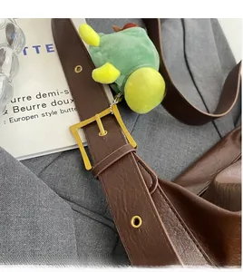 Close-up of brown leather bag strap with golden buckle and a cute turtle charm