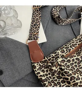 Close-up of leopard print tote bag with brown leather reinforcement and gold hardware