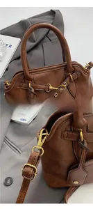 Close-up of vintage brown leather tote bag showing stitching and brass hardware detail