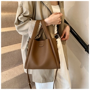 Detail of brown lychee grain leather tote bag with handles and adjustable shoulder strap