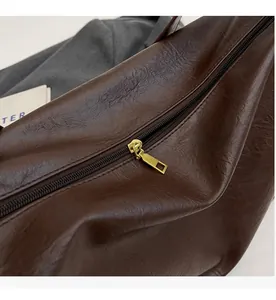 Detail of smooth gold metal zipper on dark brown vintage faux leather tote bag