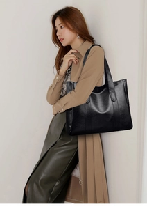 Close-up of black matte faux leather tote bag with pebble grain texture on model