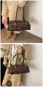 Detail of dark brown leather baguette bag featuring a detachable coin purse pendant