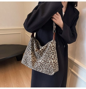 Detail of adjustable brown leather strap and classic leopard print canvas on a tote bag