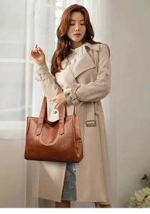 Brown PU leather tote bag with lychee texture held by a model in a beige coat