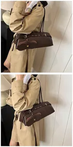 Detail of dark brown leather baguette bag with vintage gold hardware and adjustable strap