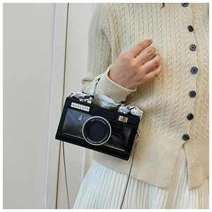 Macro view of camera-shaped bag with crystal trim and silk scarf wrapped handle
