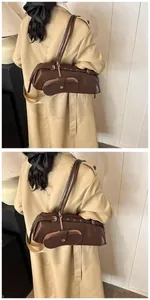 Side view of dark brown leather baguette bag with metal buckle and snap pocket on model