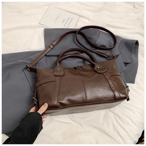 Detail of dark brown faux leather tote bag with metallic zipper and durable rivets