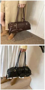 Detail of matte leather baguette bag with detachable pouch and metal eyelet design