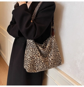 Detail of leopard print tote bag featuring wide strap and durable canvas texture on coat