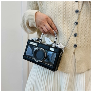 Detail of camera-shaped crossbody bag with silk scarf handle and silver chain strap