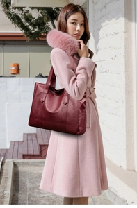 Deep red lychee texture tote bag styled with light pink coat in an outdoor setting