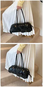 Side view of a black baguette shoulder bag featuring adjustable metal eyelet straps