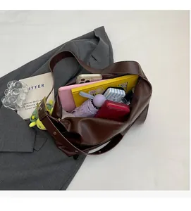 Top-down view of spacious interior of dark brown PU leather tote bag with diverse essentials