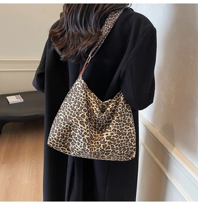 Detail of leopard print tote bag texture and wide strap on model with black winter coat