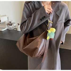 Detail view of deep brown faux leather hobo bag with adjustable strap and turtle charm