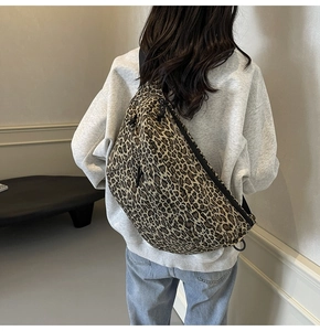 Macro detail of large leopard print crossbody bag with black zipper and wide strap
