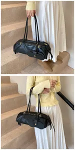 Detail of black leather baguette bag with metal eyelets and mini hanging pouch