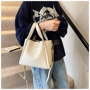Detail of off-white lychee grain leather bucket bag with gold logo and shoulder strap