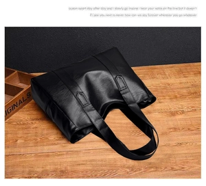Close-up of black PU leather tote bag with lychee texture on wooden surface