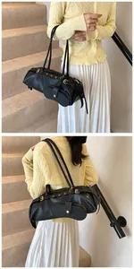 Detail of a black leather baguette bag with metal buckle and detachable coin purse